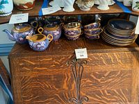 Wide view of the Nippon tea set including teapot, creamer, six teacups with saucers, and eight plates arranged on wooden surface.