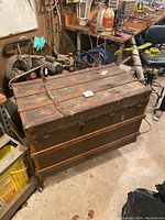 Front and side view of large wooden steamer trunk with metal bands and hardware