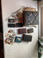 Photo showing the full assortment laid on a white cloth: large Bible, small religious books, rosary, and cards