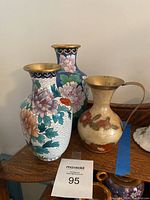 Front view of three cloisonné brass vases showing detailed floral enamel decoration.