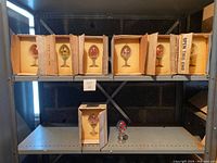 Shelf with 8 boxed Franklin Mint Faberge Eggs, all eggs inside protective foam-lined cardboard boxes.