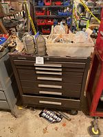 Overview of Kennedy tool box showing brown metal body, drawers, and wheels, with plastic bins and metal light cages on top.