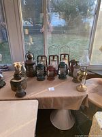 Wide assortment of lamps on table under window