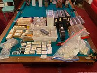 Full display of the lot on a pool table showing various coin holders, slabs, labeled coin slabs, plastic cases, and coin albums.