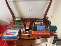 Overview of miscellaneous Lionel train parts including buildings, figures, and the Airport Hangar Kit box on display surface.