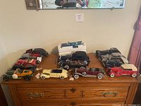 Overview of 14 diecast model cars on wooden surface