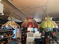 Three vintage stained glass hanging lights in red, green, and multi-color floral designs suspended from ceiling.