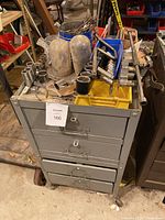 Front and side view of metal toolbox with tools on top including sockets and clamps