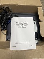 Top view of folded user guide on top of the monitor with visible cables inside original box.