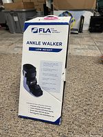 Front view of the box showing FLA Orthopedics ankle walker low height with product details and uses.
