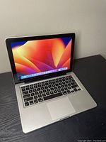 Front-left angle of open laptop with macOS Ventura on screen