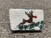 Front view of rectangular wrapped soap bar featuring a brown reindeer with red nose and green pine trees on white background.