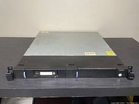 Front view of IBM 7226-1U3 multi-media enclosure showing black front panel with two purple handles and tape drive slot.