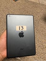 Back view of blue iPad Mini showing Apple logo and iPad text with sticker '13'