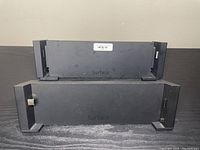 Two Microsoft Surface tablet docking stations stacked, showing front with Surface logo, plastic with adjustable grips for tablet securing