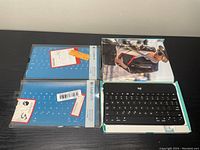 Three Bluetooth wireless keyboards shown: one black Logitech keyboard out of packaging, two teal Logitech K480 keyboards still boxed.