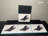 Photo of four Logitech tablet cases in original packaging arranged with one case standing upright and three cases lying flat.
