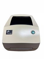 Front view of Zebra TLP 2844 thermal label printer showing beige body, black transparent cover, the Zebra logo and TLP 2844 label, and green power button.
