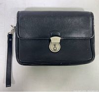 Front view of black leather Bally wristlet bag with metal lock and detachable wrist strap.