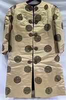 Full view of vintage Chinese silk coat with circular dark brown patterns and traditional frog closures on front.