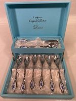 Set of six stainless steel Martin teaspoons in blue box with 'Diana' collection branding and visible blue damask-style floral pattern on handles.