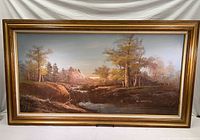 Full view of large rustic landscape oil painting in gold ornate frame showing the entire artwork including trees, mountains, and stream.