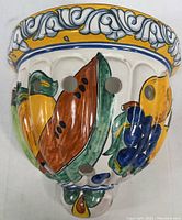 Front angle of the Talavera pottery wall planter showing detailed hand-painted fruit motif and decorative rim.