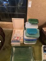 Overall stack of plastic storage bins beside open stationery box and green wooden tray