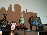 Three cloisonné vessels, carved wooden stand and metal ice bucket on shelf