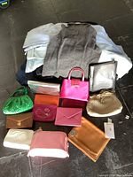 Full view of folded designer clothing in background with assortment of handbags, wallets and pouches laid out