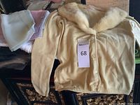 Yellow fur-trim cashmere cardigan laid flat with lot tag
