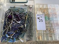 Overhead view of two clear compartment trays: left with mixed beaded strands and crucifix pendant; right with gold-tone findings including jump rings, clasps and crimp beads.