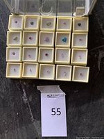 Overhead view of 20 loose faceted gemstones in foam-lined display boxes