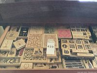 Top-down view showing a drawer filled with numerous wood block rubber stamps in varied sizes and designs including floral and key patterns.