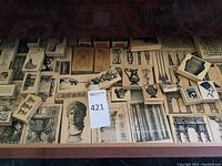 Top-down photo of a table covered with an array of wooden block rubber stamps with detailed vintage and classical designs including busts, architectural elements, animals, and artistic motifs.