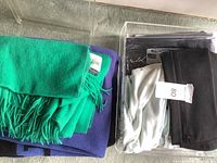 Folded green cashmere blanket, purple throw blanket, and clear box with fabric watches