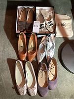 Overhead view of six pairs of designer women's shoes arranged on carpet, showing styles and colors.