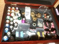 Wide view of wooden box containing sewing threads, jewelry findings, beads, brooches, and other crafting items