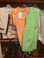 Three Valentino pieces on hangers: off-white jacket, off-white skirt, yellow and lime green dresses