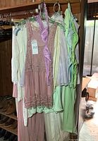 Image showing multiple women's sleepwear and dresses in pastel colors (pink, white, green, lilac) hanging on hangers.
