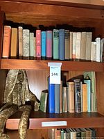 Three-shelf wooden bookcase with top and middle shelves holding vintage hardcover books and a plush bunny