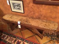 Long view of wooden bench showing top and support base against painted wall