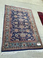 Full top view of blue floral area rug laid flat, showing overall design and fringe