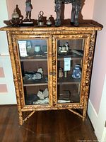 Front view of bamboo cabinet showing two hinged glass doors, interior shelves and bamboo frame