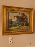 Full view of framed landscape painting on wall with sale tag