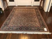 Full view of rug on hardwood floor showing overall pattern, size and wear