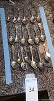 Overhead view of 19 decorative teaspoons arranged on countertop