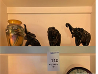 Shelf view showing art glass vase and three carved elephant figurines