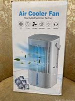Front view of boxed Air Cooler Fan showing image of the fan unit with blue airflow graphic, text stating cooling features and icons for timing, 3rd gear, low noise, 7 LED, and revolve function.