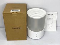 Clarston ultrasonic humidifier next to original packaging box and printed user manual.